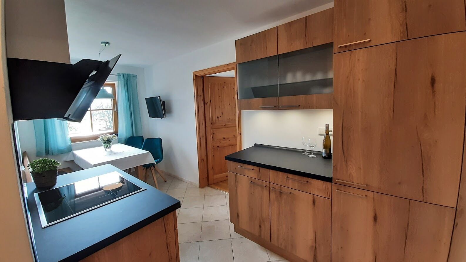 Une cuisine moderne avec des meubles en bois, un plan de travail noir et un four encastré.