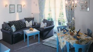 A living room with a sofa set, a coffee table, a dining table with chairs, and a chandelier.