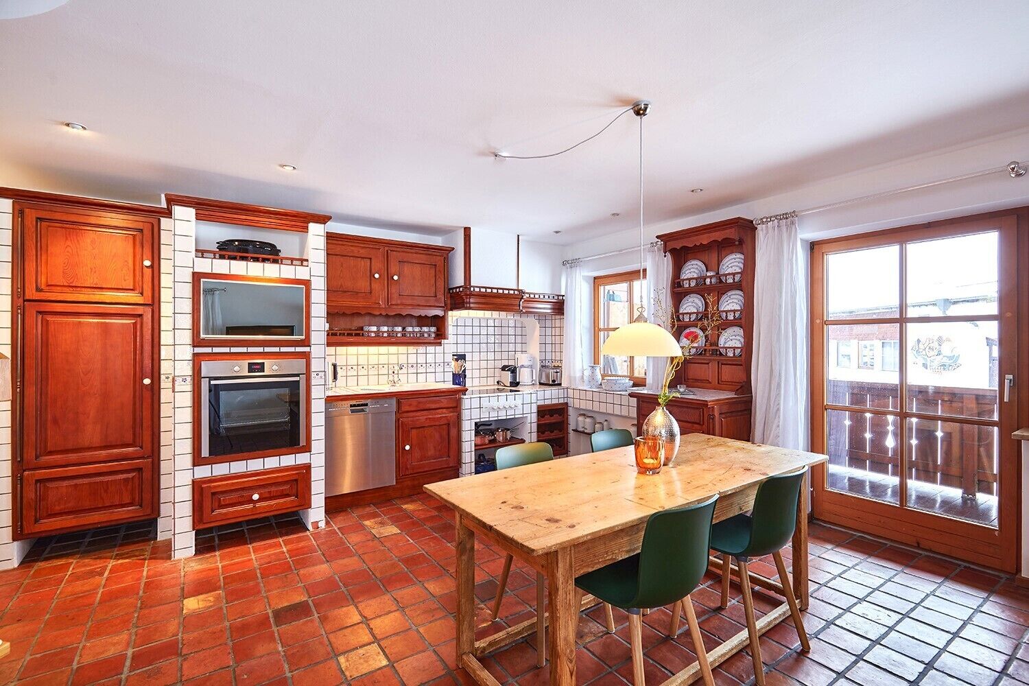 Una cocina con armarios de madera, salpicadero de azulejos, una mesa de comedor de madera con sillas y un amplio ventanal con vistas.