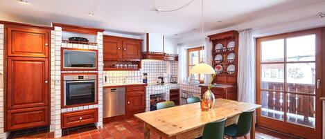 Una cocina con armarios de madera, salpicadero de azulejos, una mesa de comedor de madera con sillas y un amplio ventanal con vistas.