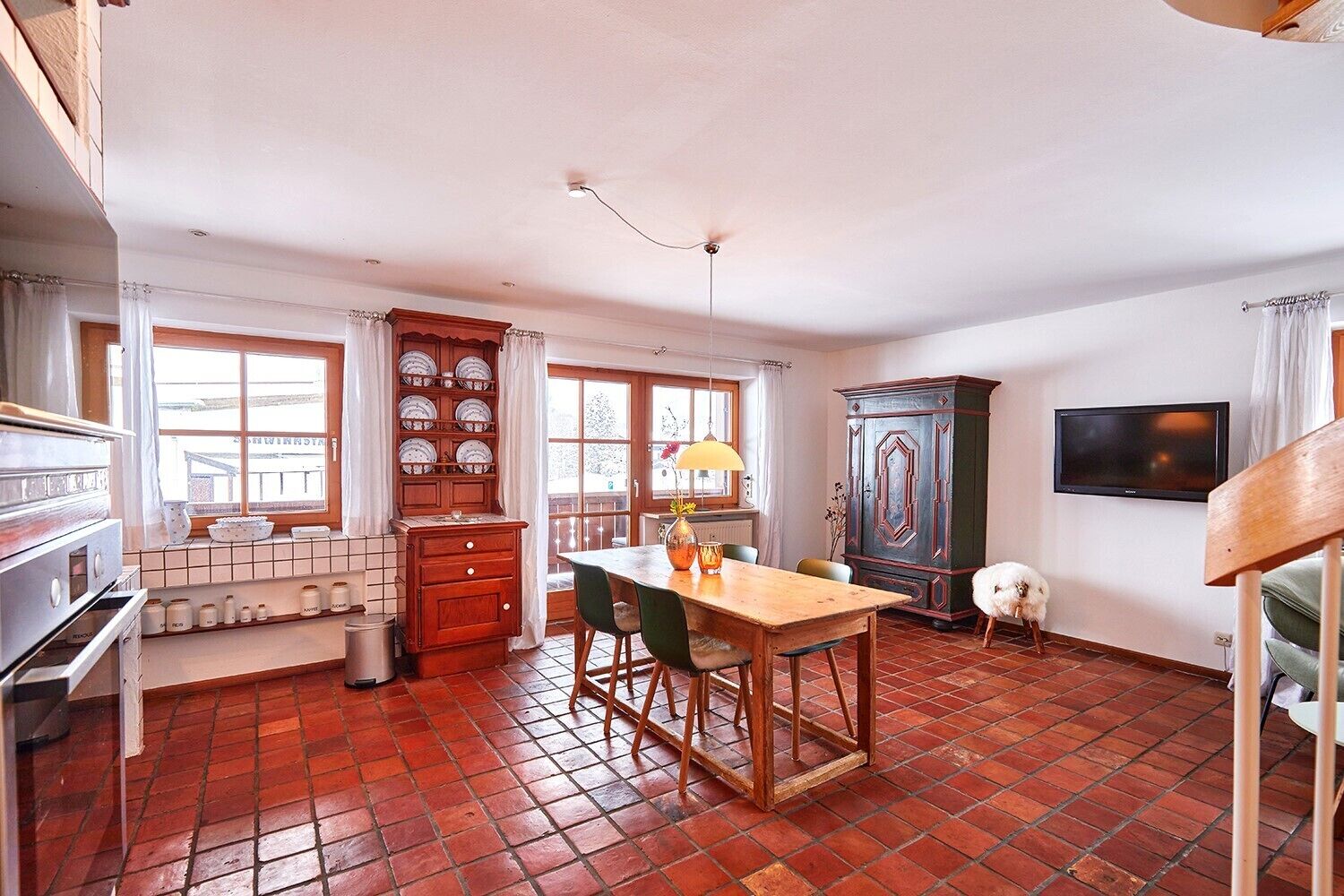 Une cuisine équipée d’une table à manger, de chaises, d’une cuisinière et d’un meuble de rangement.