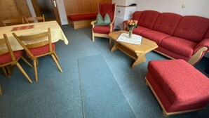 Una sala de estar acogedora con un sofá rojo, una mesa de centro de madera y una mesa de comedor con sillas.