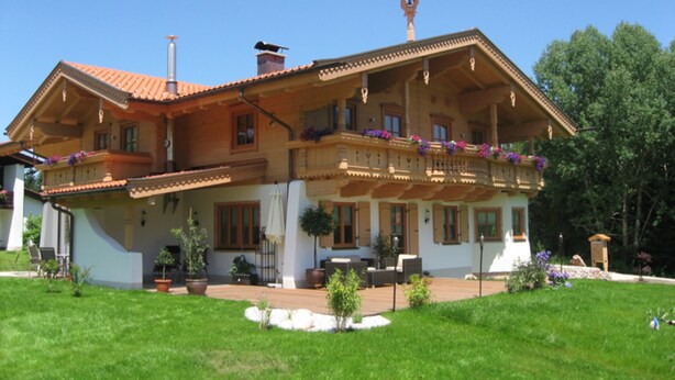 Un tipico chalet con tetto spiovente, diversi balconi e una torre con aletta a vento.