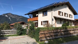 Een gebouw met twee verdiepingen, een schuin dak, zonnepanelen en houten luiken.