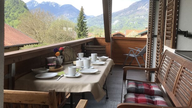 Een eetgedeelte met een tafel voor vier personen, met uitzicht op een bergachtig landschap.