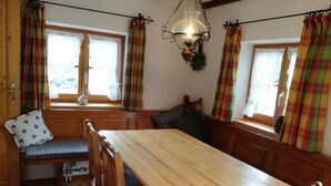 Interior acogedor de una cabaña con una mesa de comedor de madera, bancos y cortinas a cuadros.