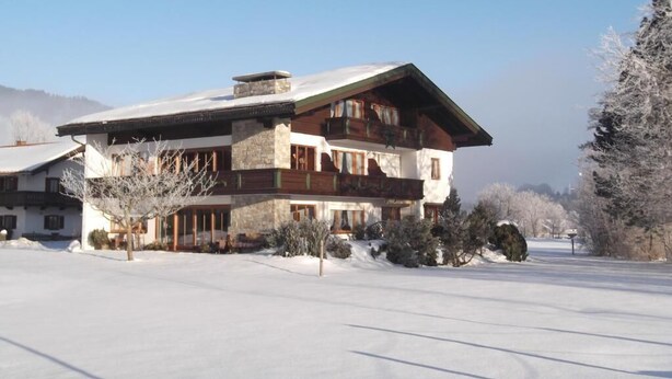 A large, two-story lodge with a stone facade and wooden accents, surrounded by snow-covered landscape.
