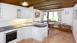 A kitchen with white cabinets, a built-in oven, a granite countertop, and a wooden ceiling.