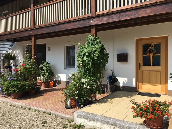 A traditional building with a wooden balcony, a door with a wreath, and various potted plants. - Ferienwohnung 2 - Seeblick (Petting)