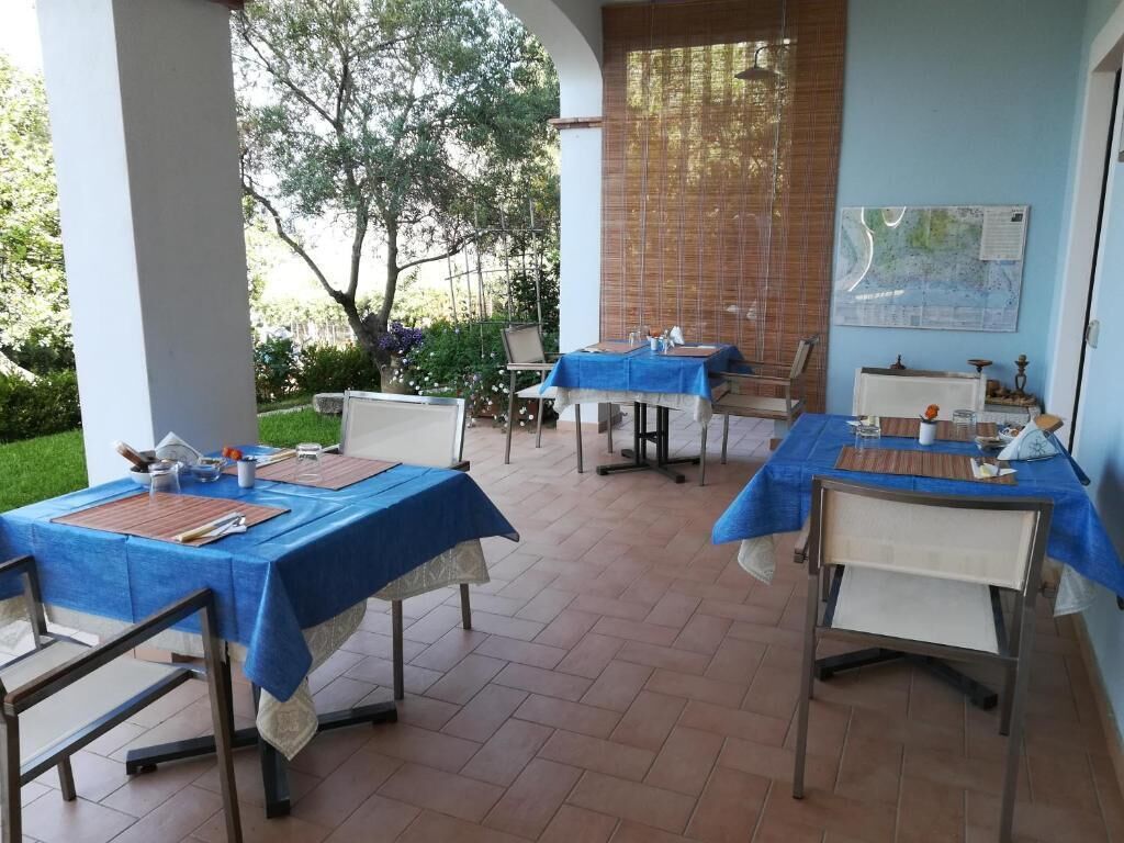 Un área de comedor al aire libre con mesas cubiertas de manteles azules, sillas y un mapa en la pared.