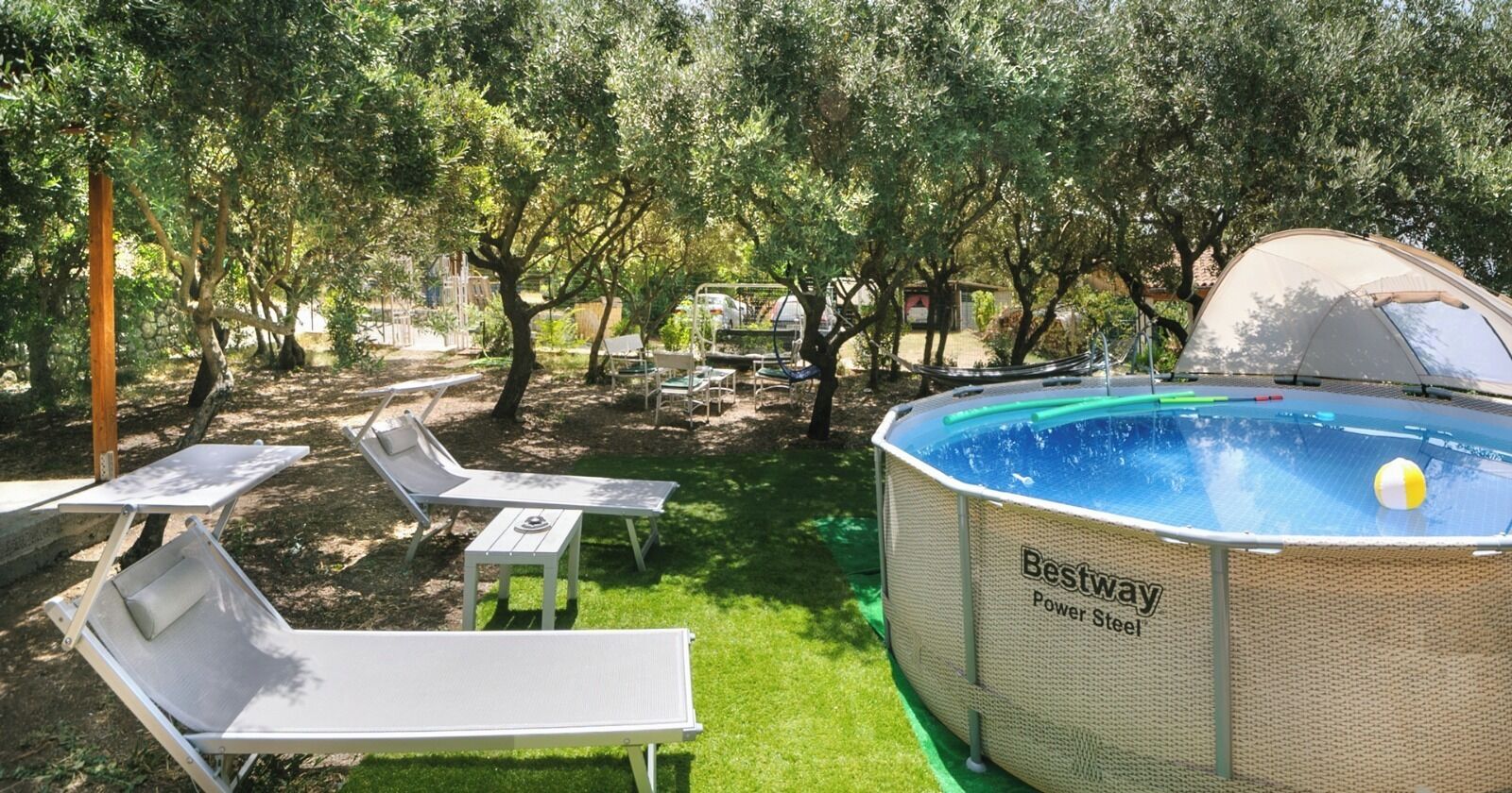 Une piscine extérieure avec des chaises longues et une tente.
