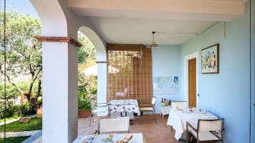 A dining area with multiple tables and chairs, a ceiling fan, and a view of the outdoors.