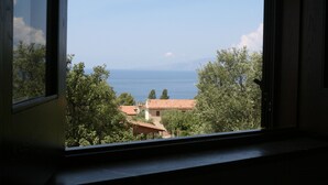 A view through a window with a clear sky, trees, and distant buildings. - B&B La Giara (Maratea)