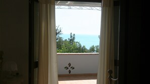A room with a bed, a window with curtains, and a view of the sea. - B&B La Giara (Maratea)