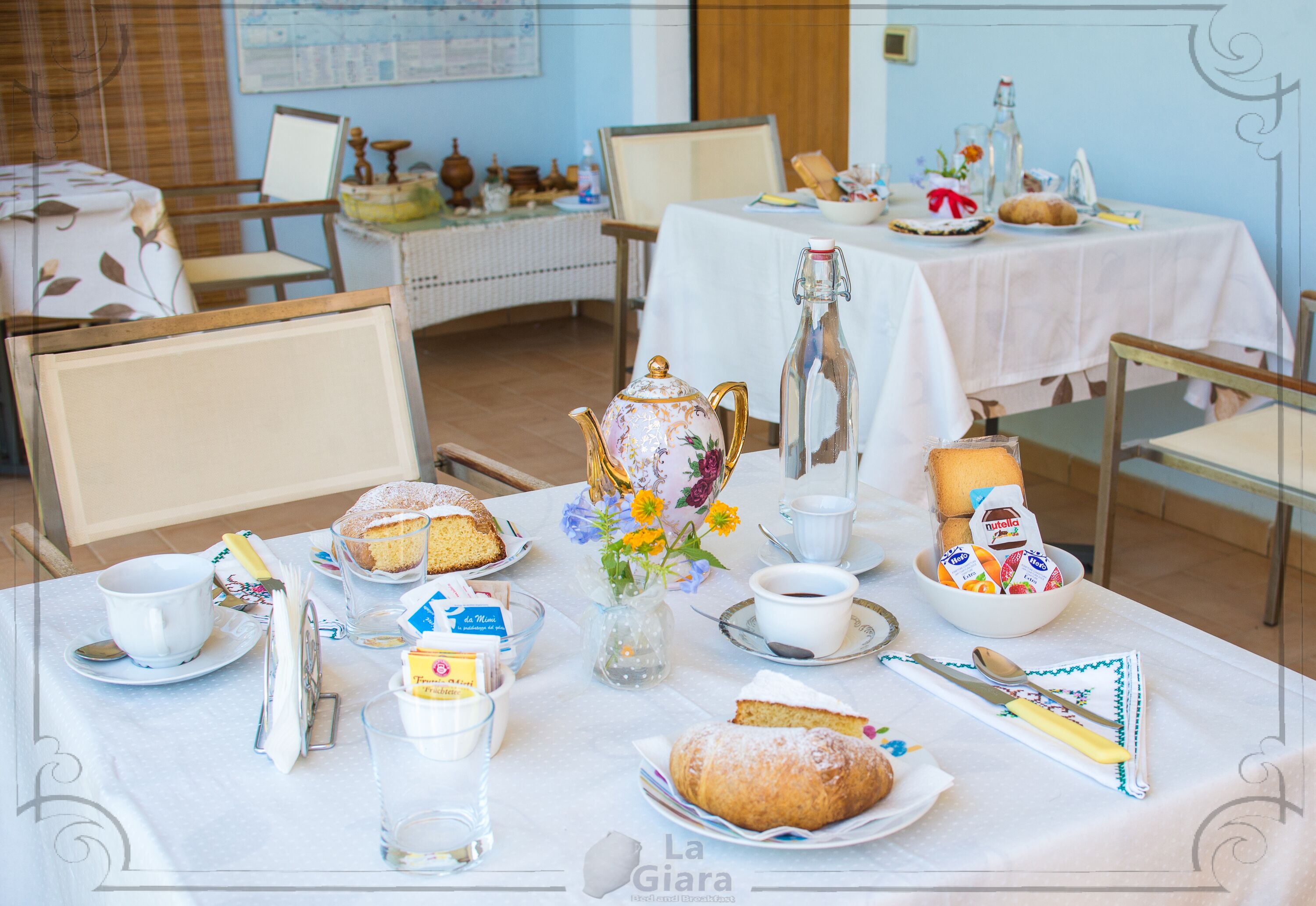 Une table à manger dressée avec divers plats, notamment des gâteaux et des pâtisseries, ainsi qu'un vase décoratif rempli de fleurs.