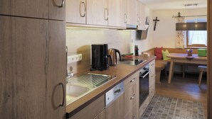 Eine moderne Küche mit Holzschränken, einer Edelstahlspüle und einem eingebauten Backofen.