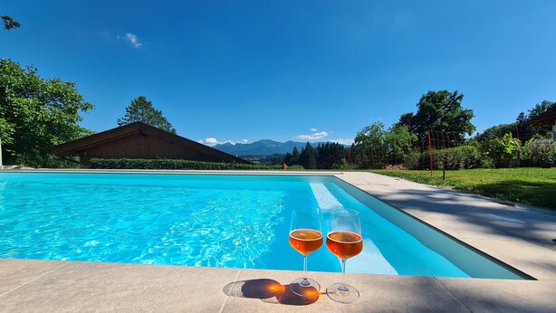 A swimming pool with clear blue water, surrounded by a tiled deck. - Holzblockhaus Hochries ***** (Rimsting)