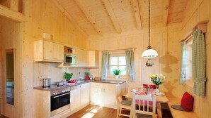 A wooden cabin with a kitchen, dining area, and a cozy seating area. - Holzblockhaus Hochries ***** (Rimsting)