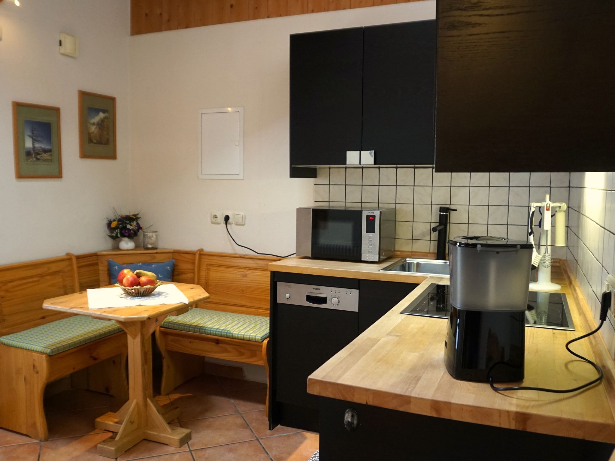 Cocina compacta con un banco de madera, microondas, cafetera y un lavabo.