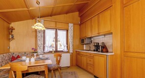 Una cucina accogliente con mobili in legno, un tavolo da pranzo con sedie, una finestra con tende e un lampadario.