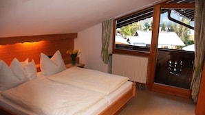 A bedroom with a wooden bed, a window with curtains, and a view of the outside.
