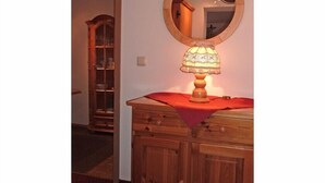 A wooden dresser with a mirror above it, a lamp on the dresser, and a wooden cabinet in the background. - Thomanhof Ferienwohnung (Ramsau bei Berchtesgaden)