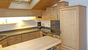 A kitchen with wooden cabinets, a countertop, a coffee maker, and a skylight. - Thomanhof Ferienwohnung (Ramsau bei Berchtesgaden)