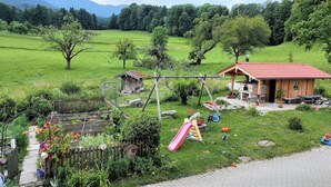 Une propriété rurale comprenant une maison en bois, un jardin, une balançoire et un toboggan.