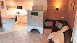 Un intérieur de chalet chaleureux avec une petite cuisine, un canapé avec des coussins et un plafond en bois.