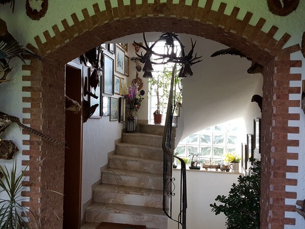 A staircase with a brick archway, surrounded by framed pictures and potted plants.