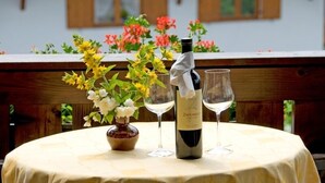 Een ronde tafel met een fles wijn en twee wijnglazen, omringd door bloemen.