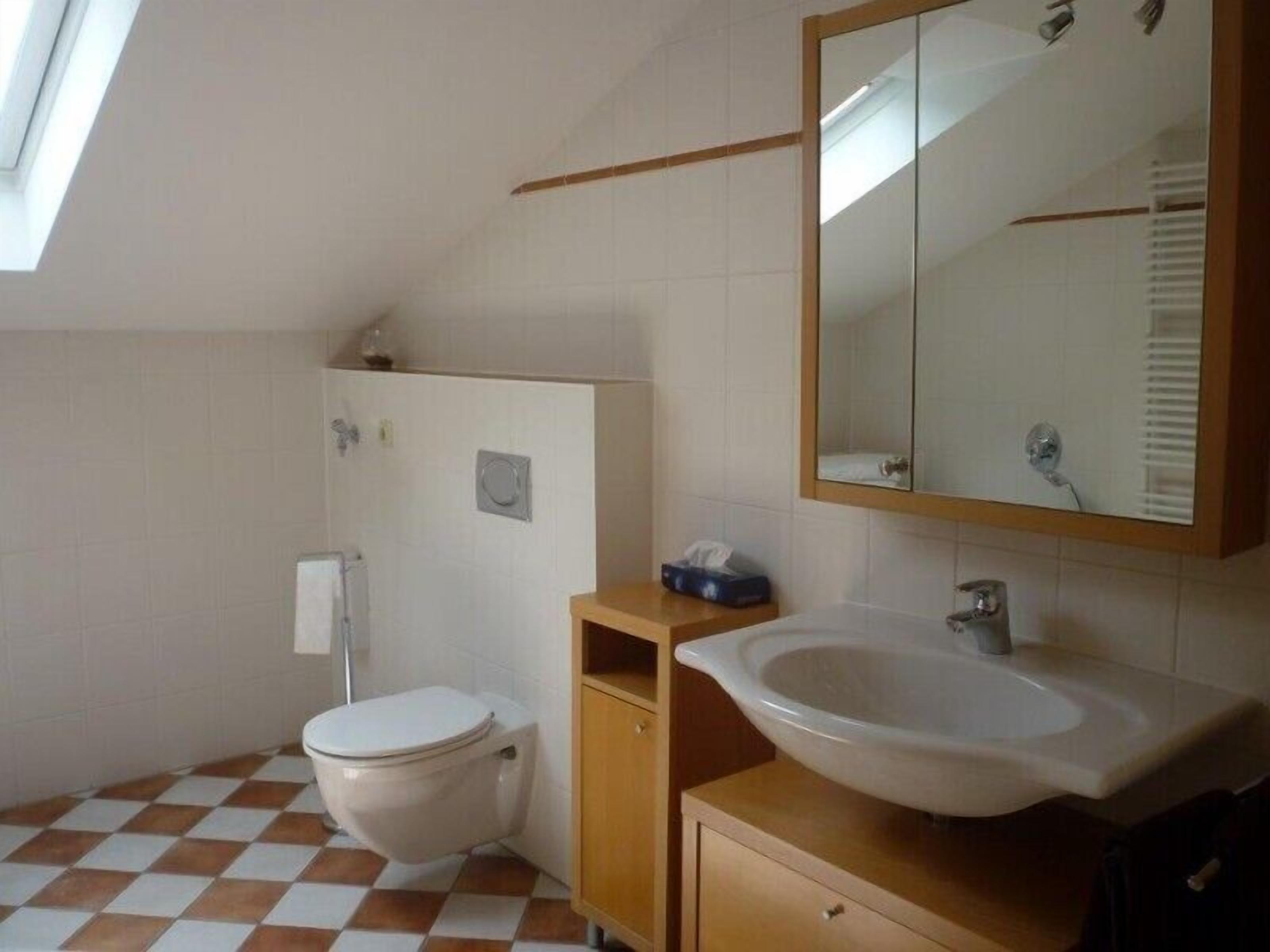 A small, clean bathroom with a toilet, sink, and mirror.