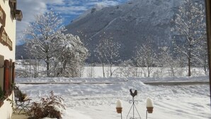 Schneebedeckte Landschaft mit einem Berg im Hintergrund, einer Bank und einem Zierhahn.