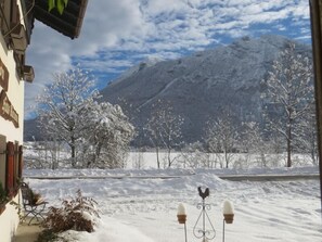 A snowy landscape with a mountain in the background, a bench, and a decorative rooster.