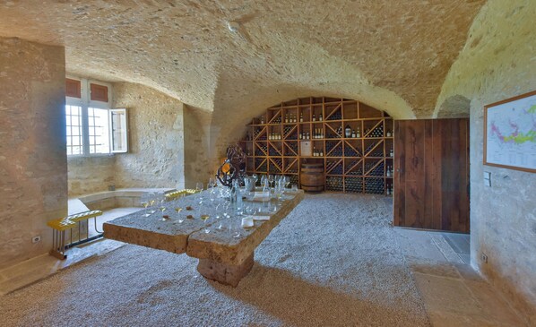 Un interior con techo de piedra, una botellera y una mesa con copas.