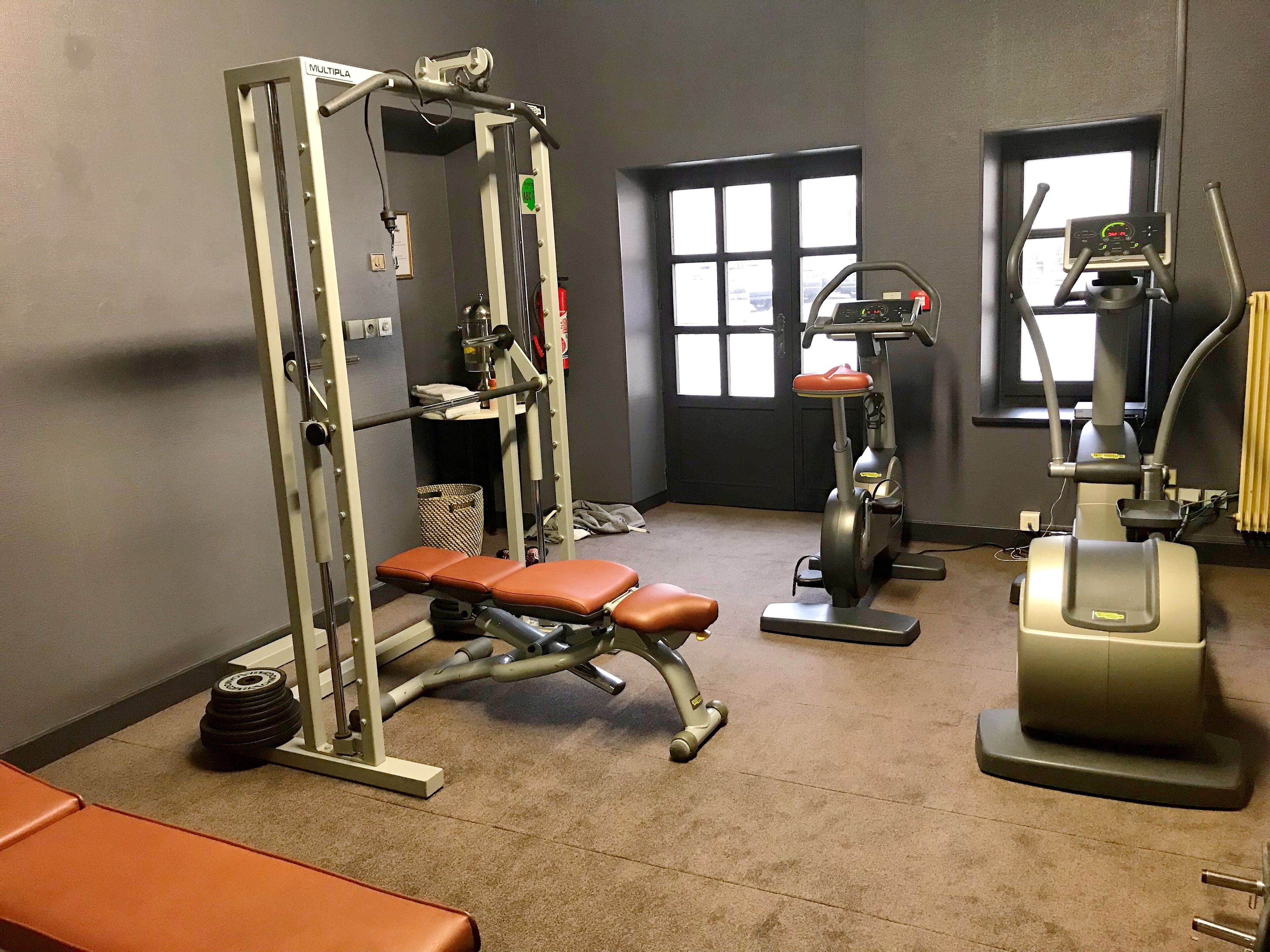 A gym with a bench, weight machine, and elliptical.