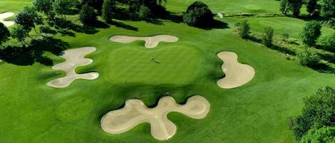 Eine Vogelperspektive auf einen Golfplatz mit Sandbunkern und Bäumen.