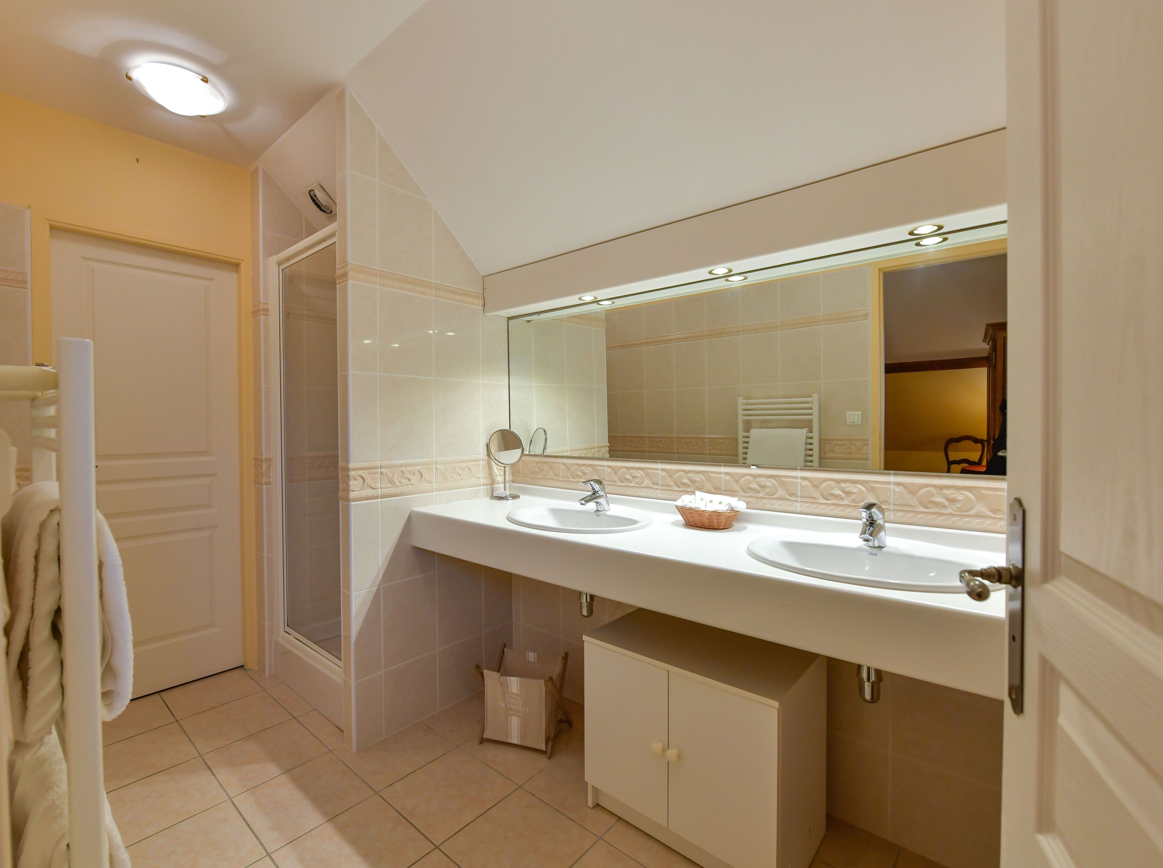 Une salle de bain avec deux lavabos, un grand miroir et un porte-serviettes.