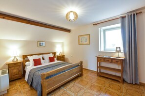 Un dormitorio con cama de madera, mesitas de noche, un escritorio y una ventana con cortinas.