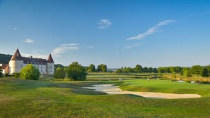A golf course with a castle in the background, sand bunkers, and a pond. - Le clos champagnac at Hotel Golf Chateau de Chailly (Chailly-sur-Armancon)
