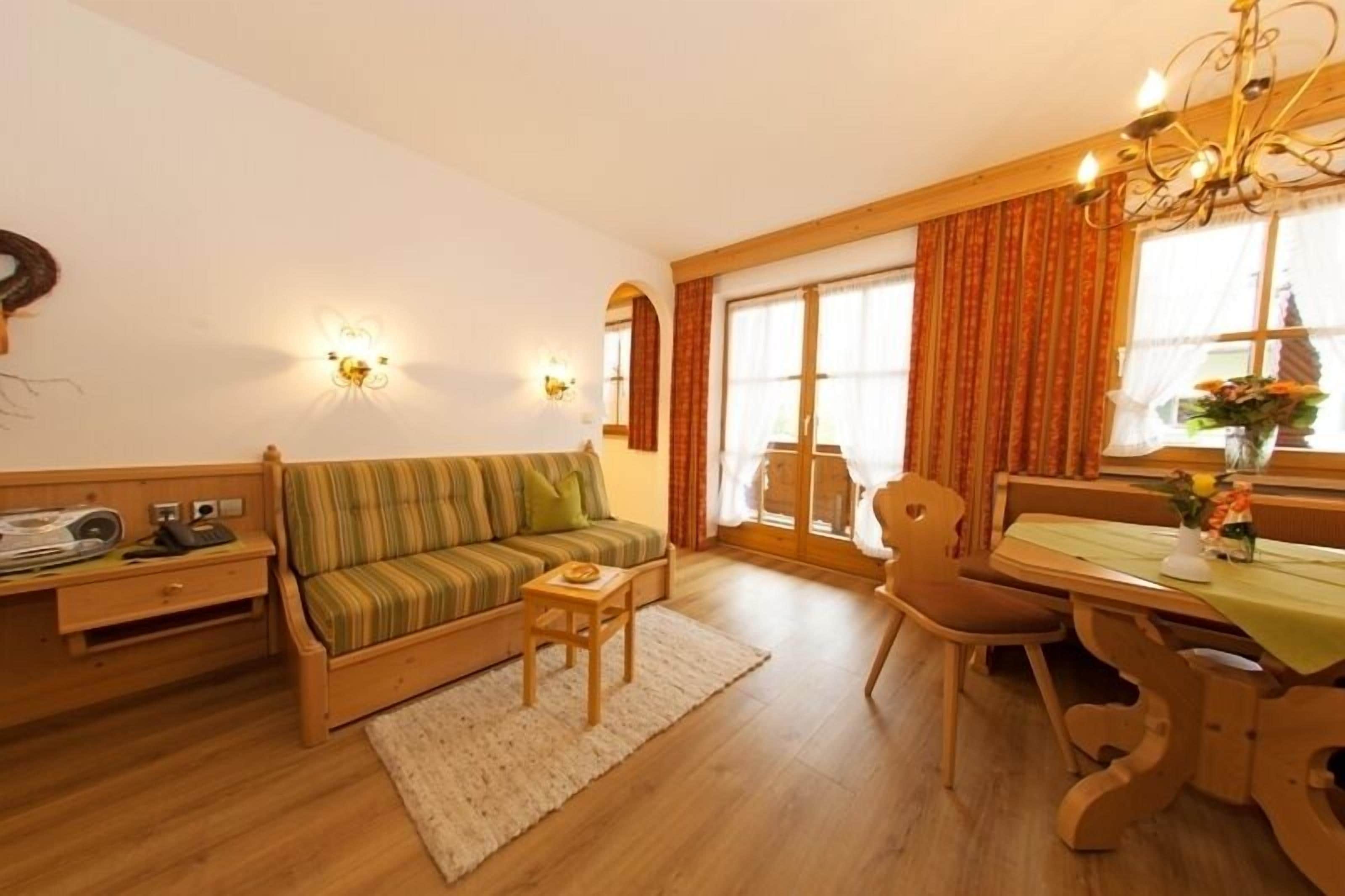 Ein gemütliches Wohnzimmer mit einer Couch, einem kleinen Tisch und einem Essbereich mit Tisch und Stühlen.