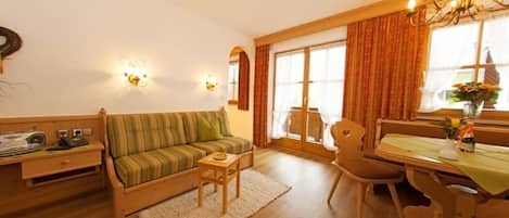 Ein gemütliches Wohnzimmer mit einer Couch, einem kleinen Tisch und einem Essbereich mit Tisch und Stühlen.