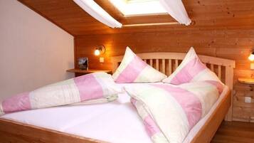 Ein Bett mit hölzernem Kopfteil, ein Nachttisch mit Lampe und ein Oberlicht darüber.
