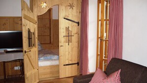 Ein gemütliches Zimmer mit einem hölzernen Bett, einem Fernseher und einem karierten Vorhang.