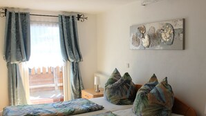 Un dormitorio con cama, dos almohadas, una mesita de noche, una lámpara y una obra de arte en la pared.
