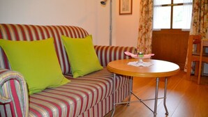 A striped sofa with green cushions, a round wooden table with a glass, and a chair. - (3) One-room apartment, approx. 25 m², kitchenette and balcony (Reit im Winkl)