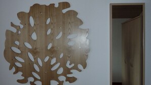 A wall with a large wooden tree cutout and a doorway leading to another room. - Two-room apartment, 40m², bedroom and living room, kitchenette, balcony (Reit im Winkl)