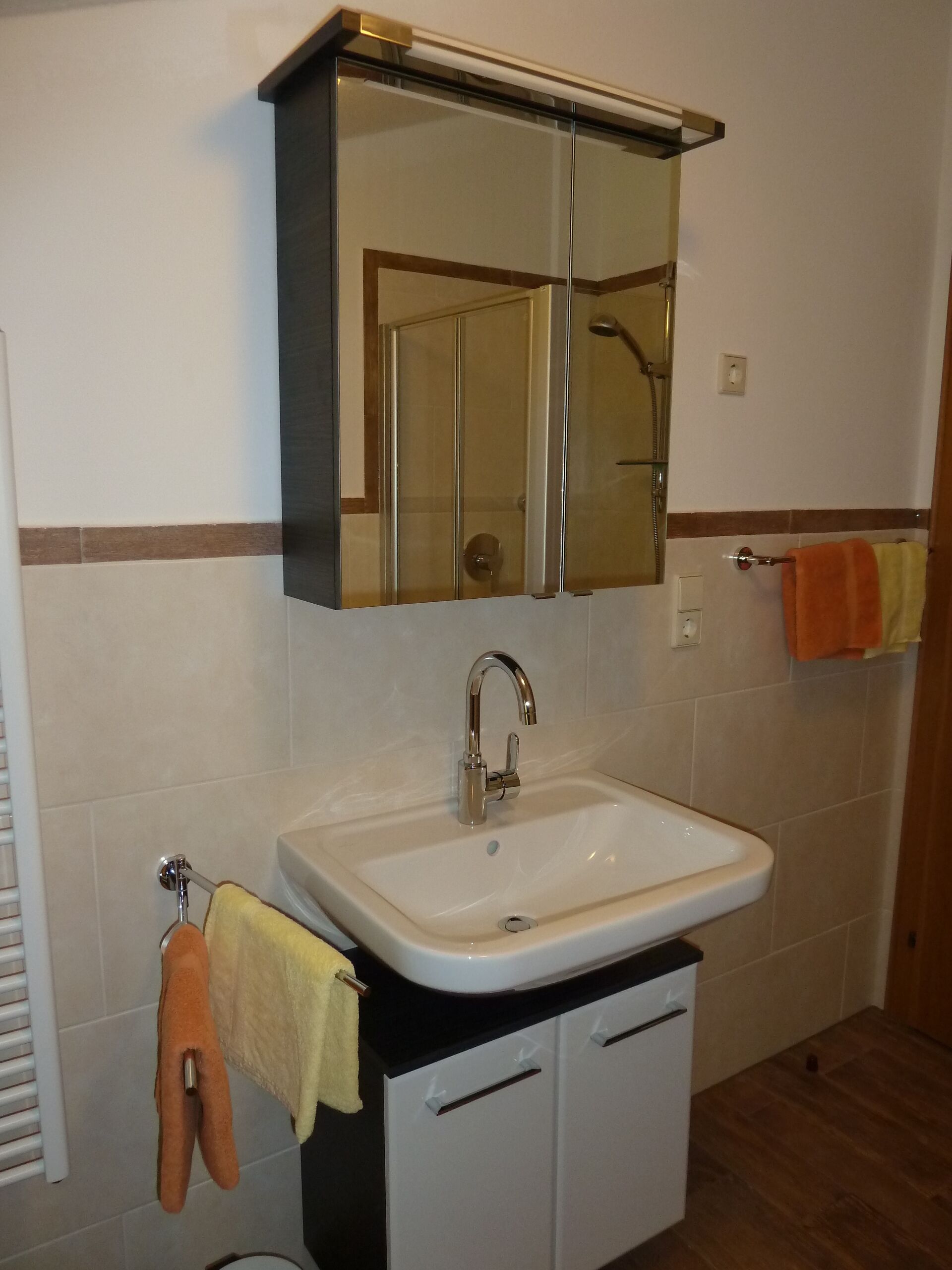 A bathroom with a white sink, a mirror above it, and a towel rack with towels.