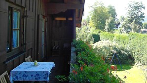 Una habitación con una mesa lista para comer, una ventana y vistas a un jardín con un columpio.