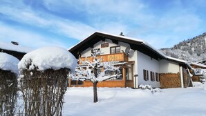 A two-story chalet with a wooden facade, a balcony, and a sign indicating it is a restaurant. - Ferienwohnung 50qm, Allergikerfreundlich, Küche, Dusche/WC, Südbalkon (Reit im Winkl)